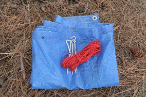 A tarp, 50 feet of parachute cord or light rope and four aluminum tent stakes are the basis of a quick shelter.