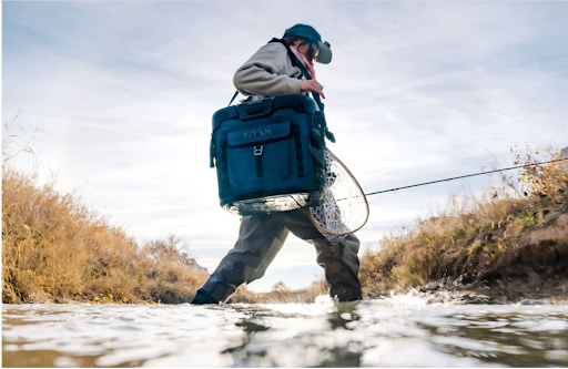 angler walking across river with cooler