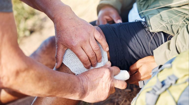 person treating a knee wound outdoors