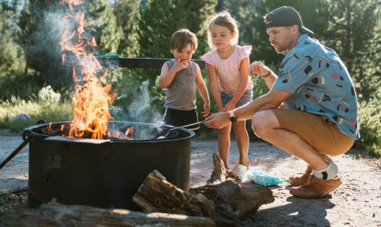 parent with two children around campfire roasting marshmallows