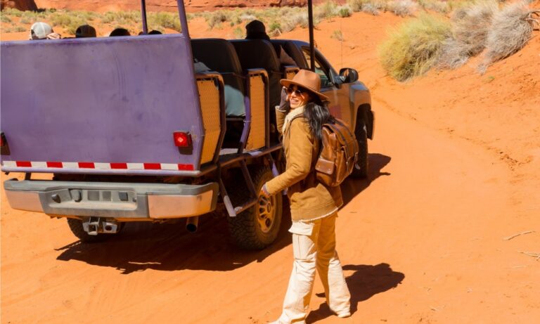 woman standing next to jeep tour vehicle in desert