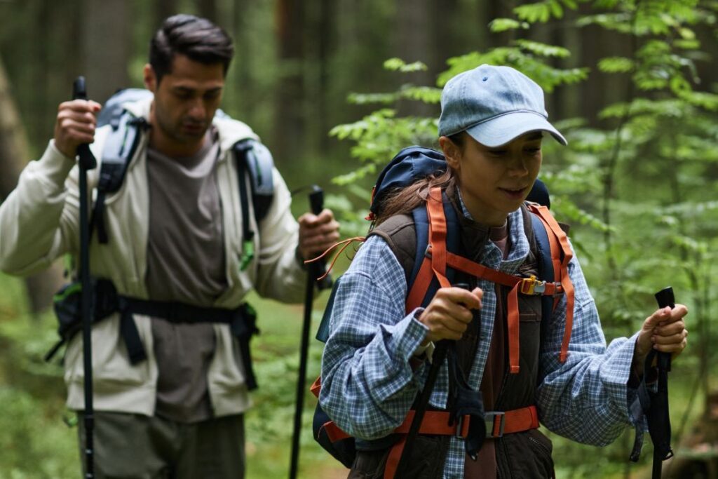 two people walking on wooded trail with hiking poles