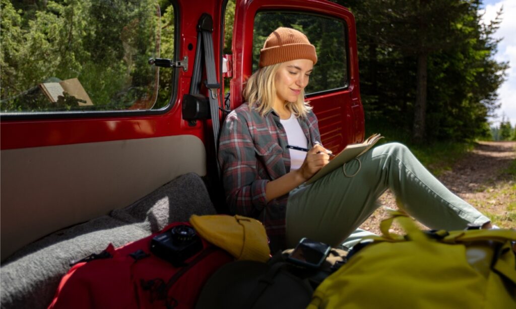 girl camping in van writing in a journal