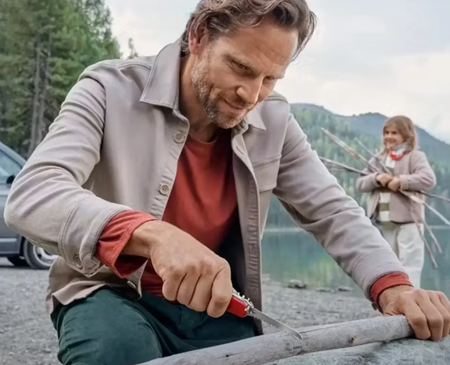 man using swiss army knife on driftwood